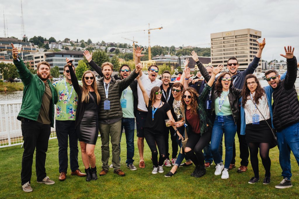 A group of attendees cheer for a photo during a lawn party at Postback 2016