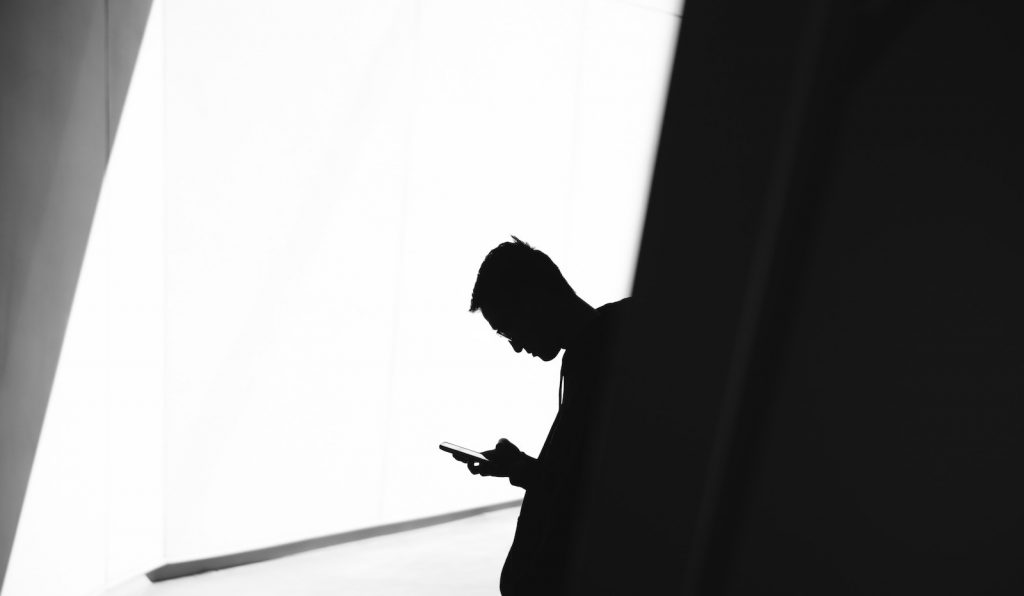 Photo of man holding mobile phone in shadow
