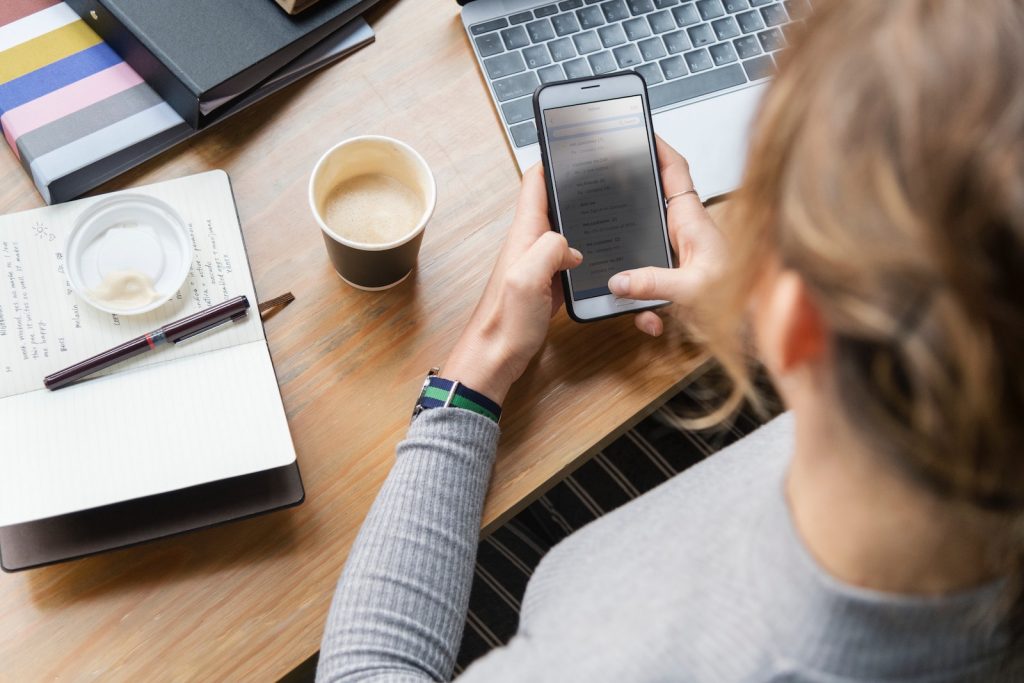 A media buyer answers emails on her mobile phone as she plans her marketing goals for the day.