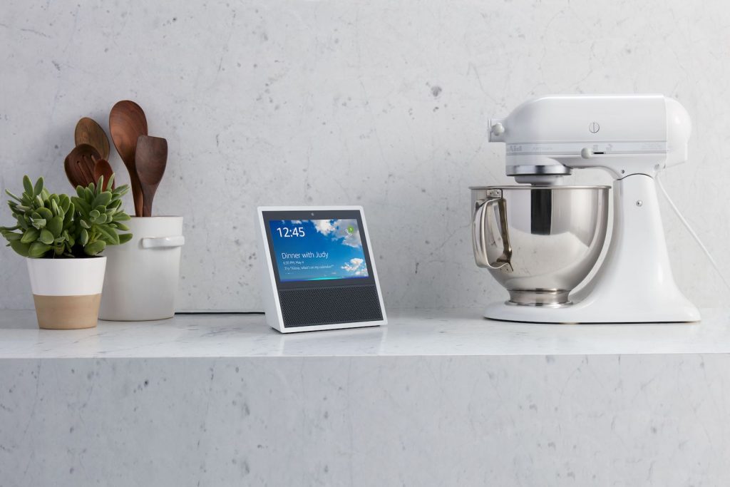 An Amazon Echo Show sits on a kitchen counter next to a mixer.