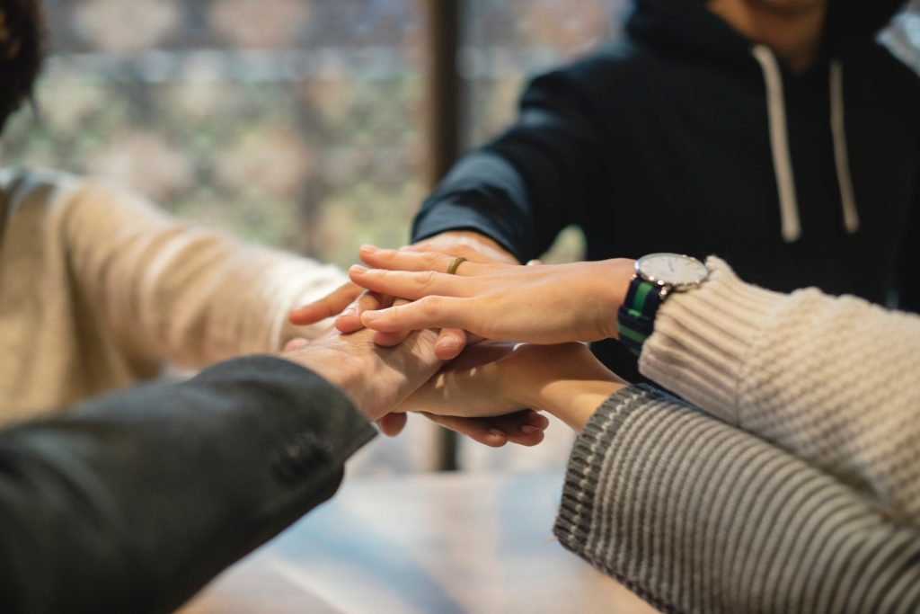 Photo of coworkers in office putting their hands in.