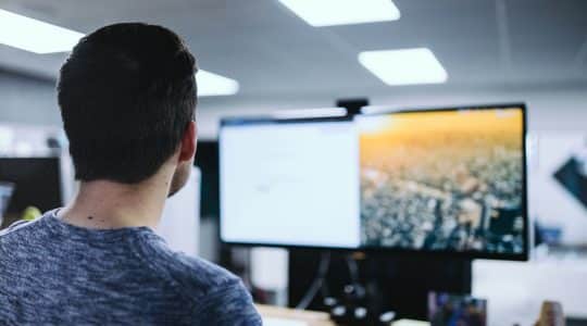 Man looking at computer monitors