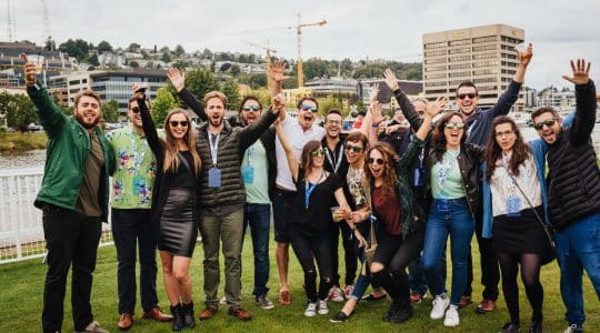 A group of attendees cheer for a photo during a lawn party at Postback 2016