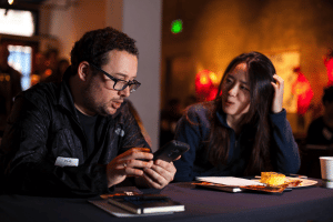 Two people sitting and looking at phones