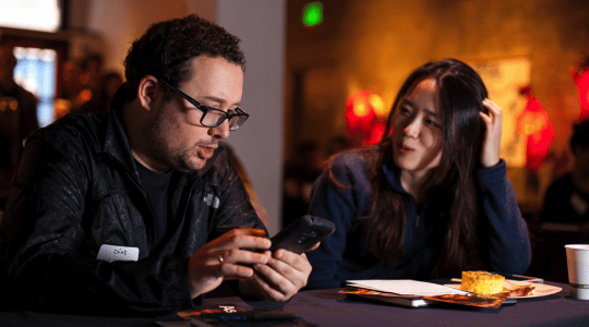 Two people sitting and looking at phones