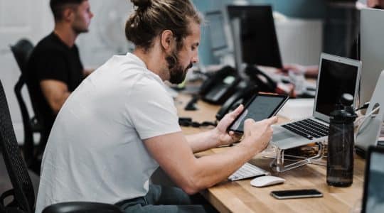 Man sitting at desk testing links on a laptop and tablet