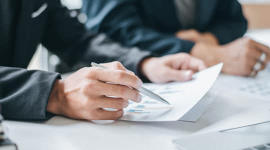 Closeup of hands and paper in meeting for the Credit Sesame TUNE case study