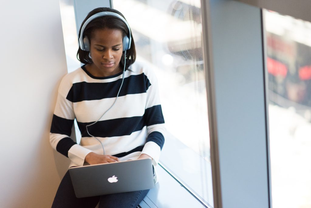 Woman with headphones watching a webinar on her laptop