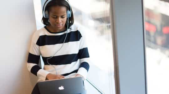 Woman with headphones watching a webinar on her laptop