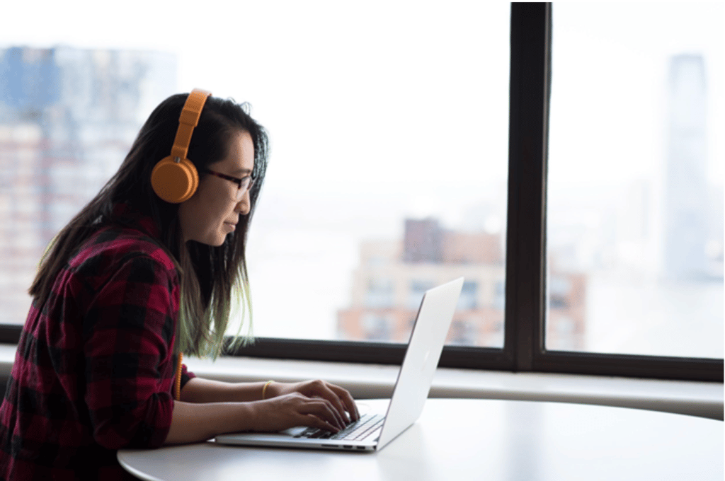 A woman listens to a webinar while she types on the computer