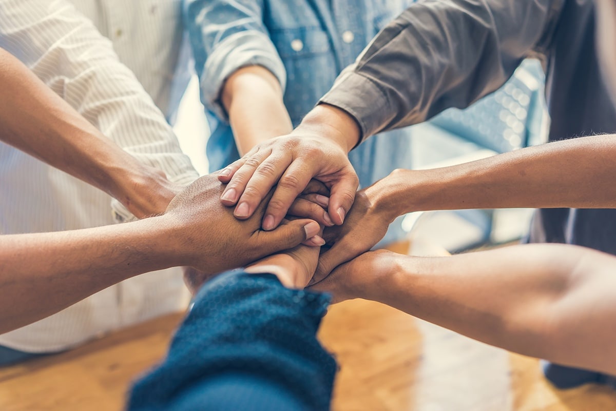 Foto de um grupo de pessoas com as mãos unidas para o fundo das avaliações