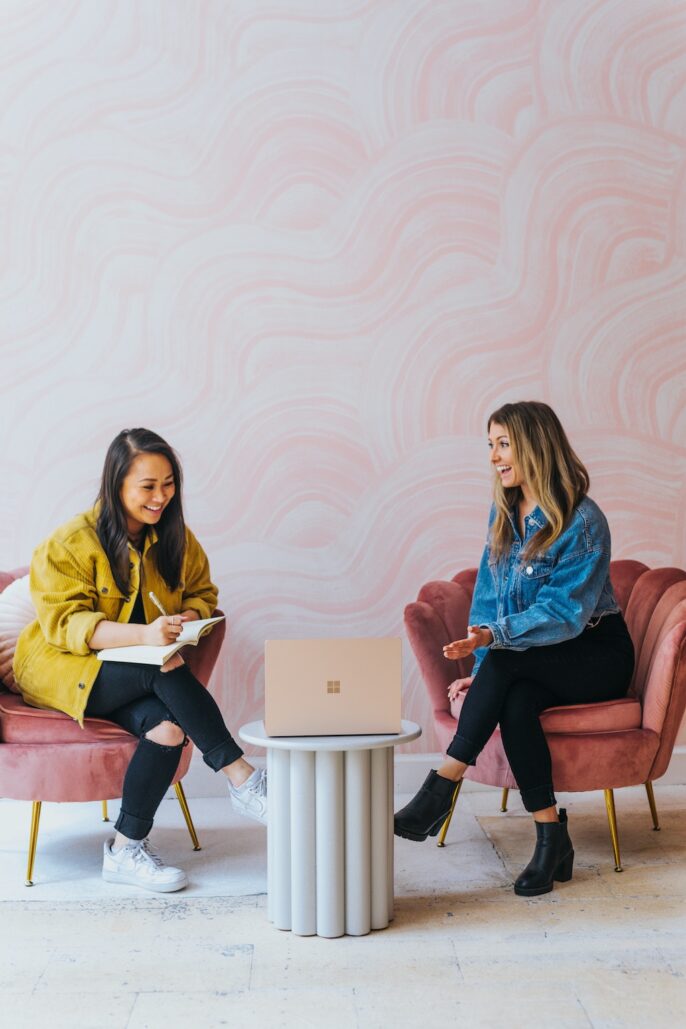 An affiliate manager shows a brand marketer a campaign on her laptop.