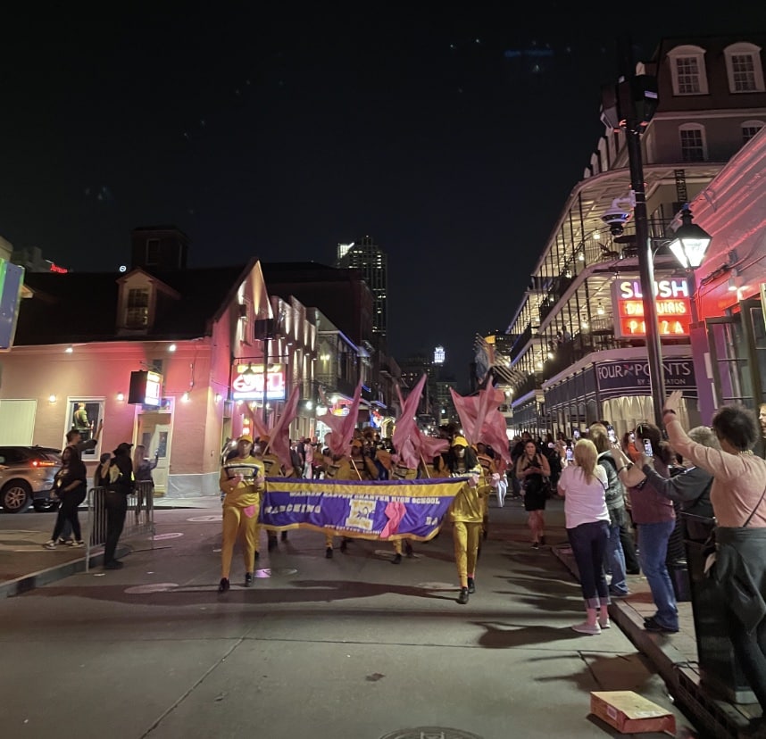 A marching band goes down the street in the French Quarter in New Orleans