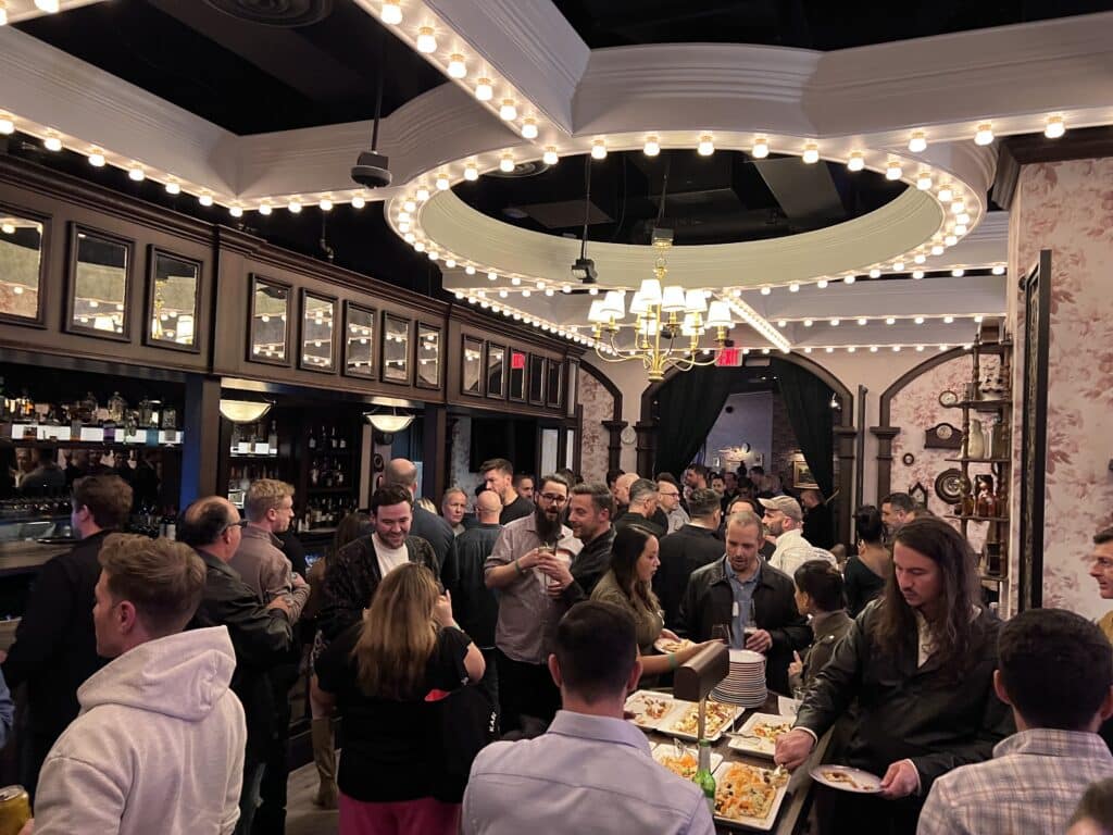 Attendees enjoying food and beverages at the TUNE Happy Hour in Flight Club Las Vegas during Affiliate Summit West